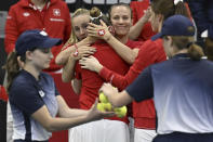 Switzerland's Celine Naef, center, is embraced by teammates Jil Teichmann, left, and Victoria Golubic , after a Billie Jean King Cup qualification round tennis match against Poland's Magdalena Frech at the Jan Group Arena in Biel, Switzerland, Friday, April 12, 2024. (Peter Schneider/Keystone via AP)
