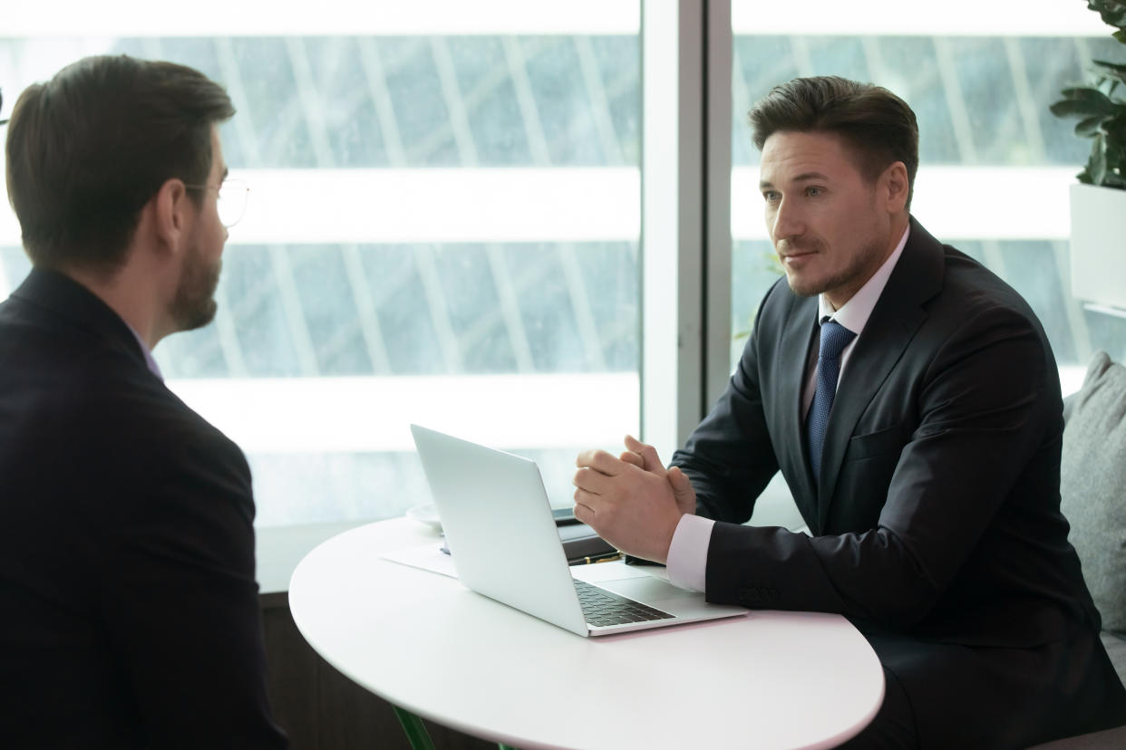 Concentrated confident male hr manager holding interview with young job seeker in modern office. Focused pleasant employer listening to candidate self presentation during one on one meeting.