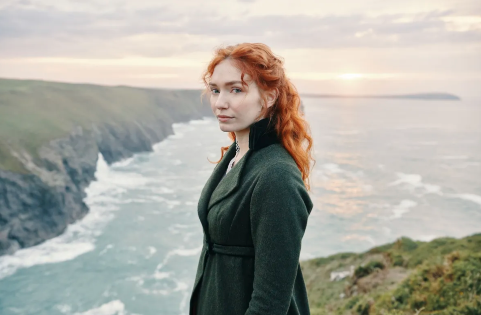 a woman standing on a hill overlooking a body of water