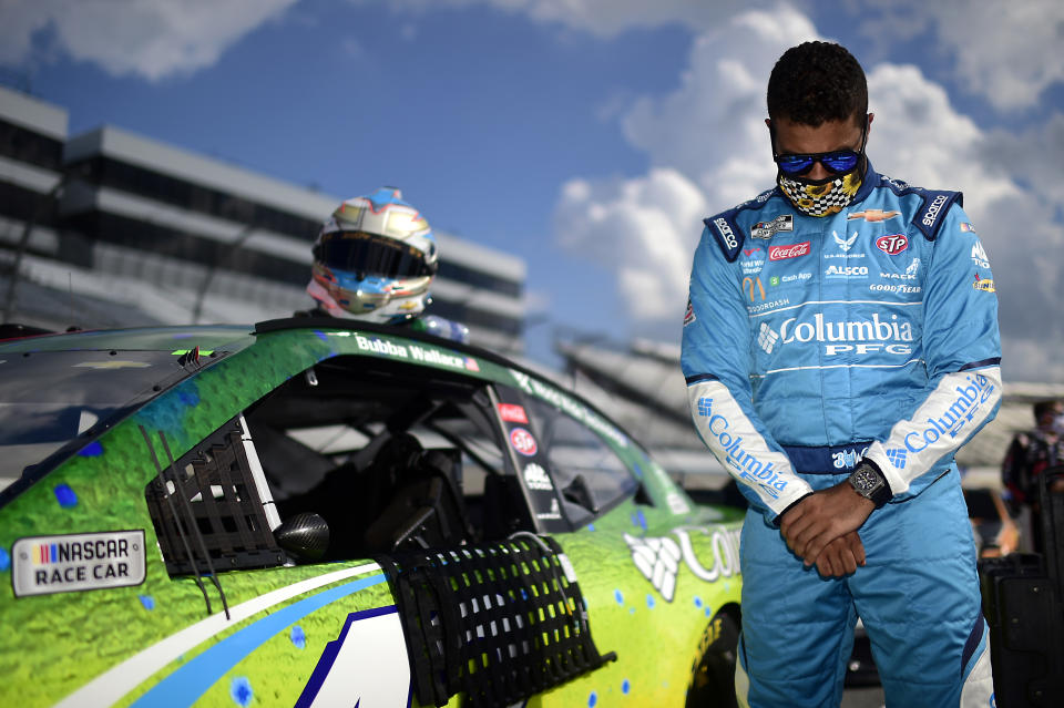 Bubba Wallace stands with his head bowed next to his car during the pre-race ceremonies prior to the NASCAR Cup Series Drydene 311 at Dover International Speedway.