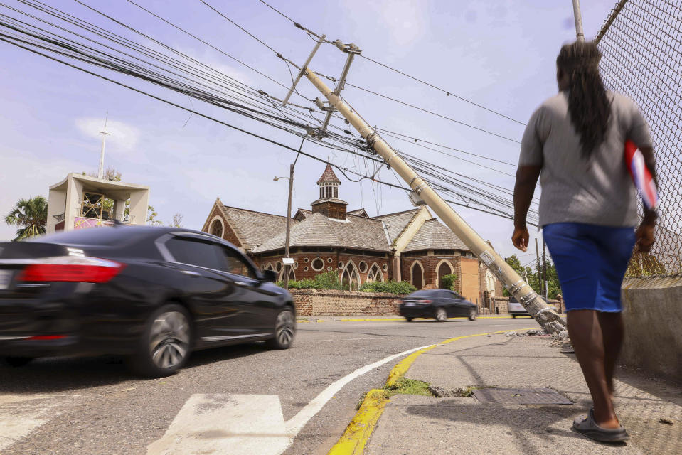 Cars drive under a leaning utility pole in the aftermath of Hurricane Beryl in Kingston, Jamaica, Thursday, July 4, 2024. (AP Photo/Leo Hudson)