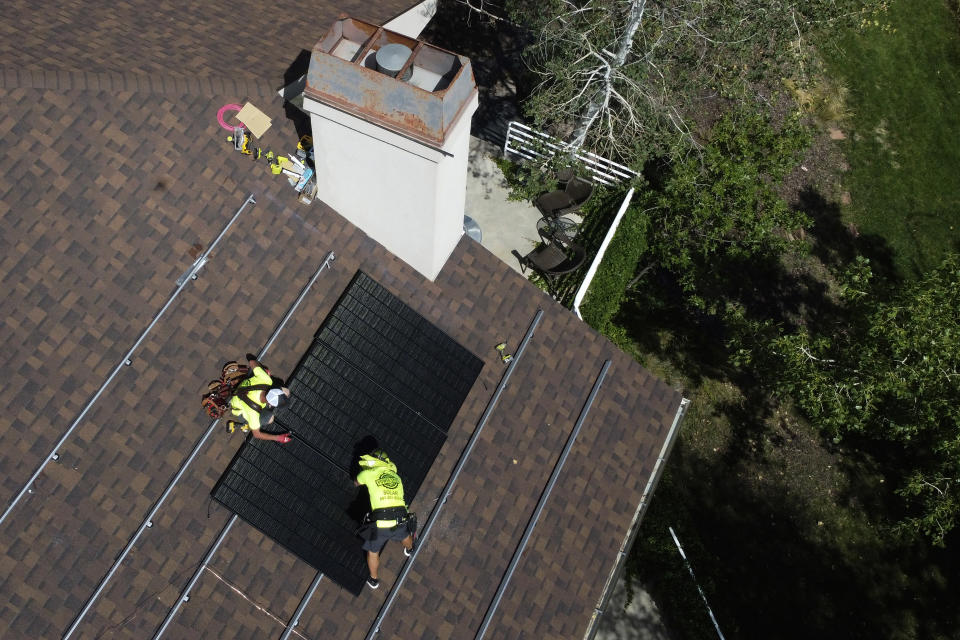 FiLE - Workman with Power Shift Solar put solar panels on a house, Aug. 10, 2022, in Salt Lake City. The Biden administration is announcing Thursday, April 20, 2023, more than $80 million in funding as part of a push to make more solar panels in the U.S. and make solar energy available in more communities. (AP Photo/Rick Bowmer, File)