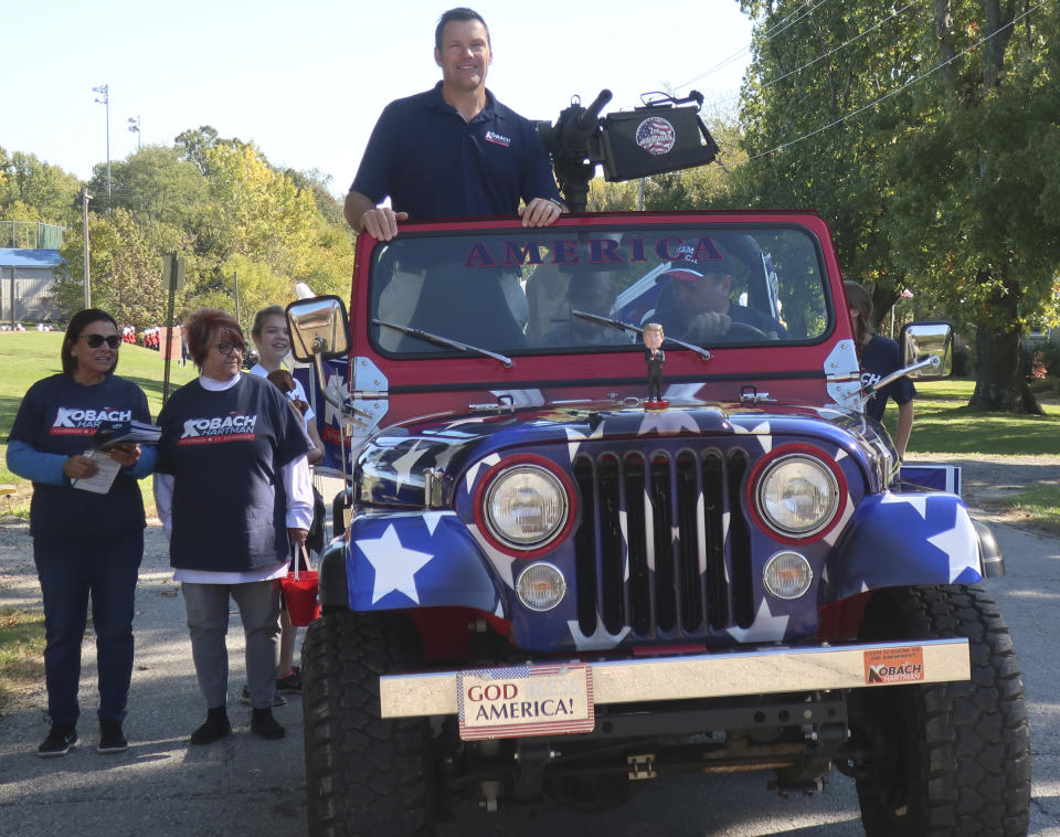 In this photo from Saturday, Oct. 20, 2018, Kris Kobach, then the Kansas secretary of state and the Republican nominee for Kansas governor, rides in a parade in a jeep with a replica machine gun in Baldwin City, Kan. The jeep was the signature prop in Kobach's campaign for governor that year, which he lost to Democrat Laura Kelly. (AP Photo/John Hanna)