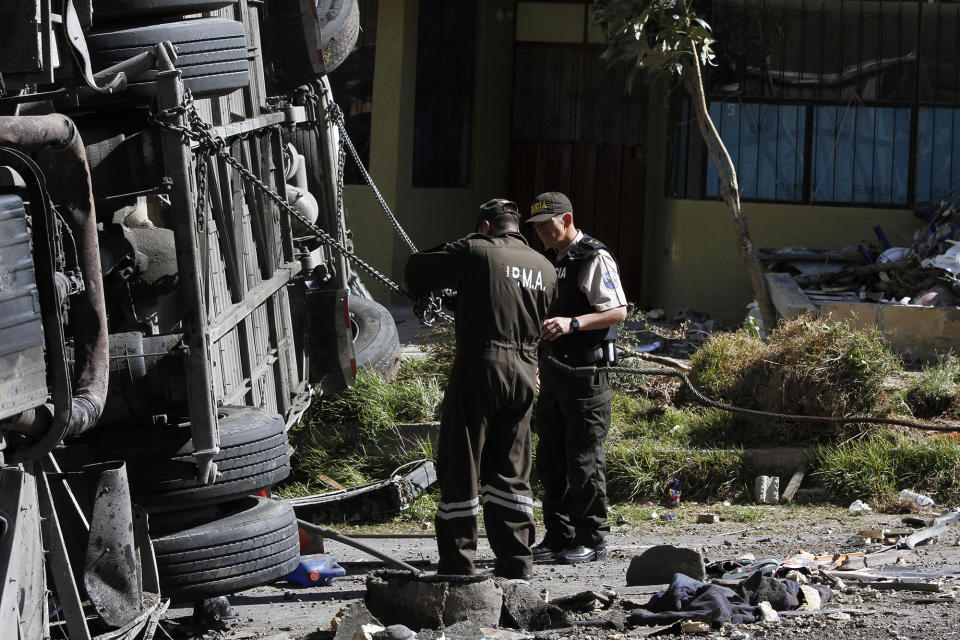 Police officers prepare salvage a vehicle that collided with a Colombian-registered bus traveling to Quito, in Pifo, Ecuador, Tuesday, Aug. 14, 2018. At least 24 people were killed and another 19 injured when a bus careened into another vehicle at high speed and overturned along the Pifo-Papallacta highway, near Ecuador's capital, local officials reported. (AP Photo/Carlos Noriega)