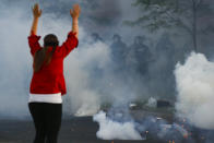 Tear gas canisters detonate beside a protester as authorities clear an intersection near the Minneapolis 5th Police Precinct, Saturday, May 30, 2020, in Minneapolis. Protests continued following the death of George Floyd, who died after being restrained by Minneapolis police officers on Memorial Day. (AP Photo/John Minchillo)