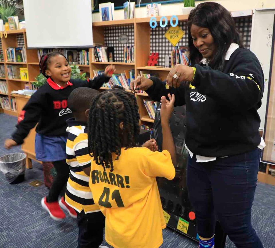 Westside Elementary Media Specialist Lakeisha Byrd hands out coins to students Christiana Hepburn, Kenton Strachan and Trey Powers Jr. to use in the school's new book vending machine.