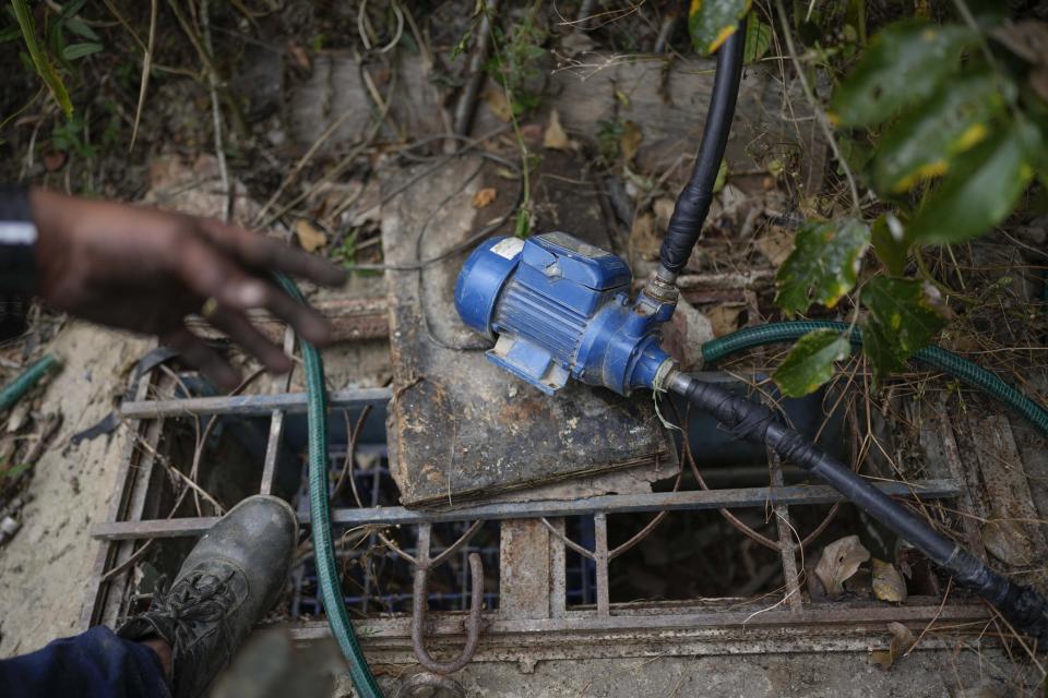 Franklin Caceres checks a water pump he used to collect a groundwater from well in the Petare neighborhood of Caracas, Venezuela, Monday, March 20, 2023. Caceres supplies water to more than 400 people in the upper sector of Petare as the celebration of World Water Day on March 22 is set to coincide with the start of the UN 2023 Water Conference in New York, aimed at solving the water and sanitation crisis. (AP Photo/Matias Delacroix)