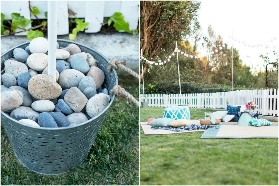 <p>You don't need a covered patio to create some ambience. Fill buckets with stones to anchor a ring of <a href="https://www.goodhousekeeping.com/food-recipes/party-ideas/tips/a32365/emily-henderson-target-spring-entertaining/" rel="nofollow noopener" target="_blank" data-ylk="slk:festive party;elm:context_link;itc:0;sec:content-canvas" class="link ">festive party</a> lights. </p>