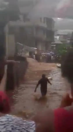 A person walks through floodwater in the town of Foulah, following a mudslide on the outskirts of Freetown, Sierra Leone, in this still image obtained from a social media video taken August 14, 2017. Video taken August 14, 2017. Kelvin Kamara and Fuhard Sesay / Social Media Website via REUTERS