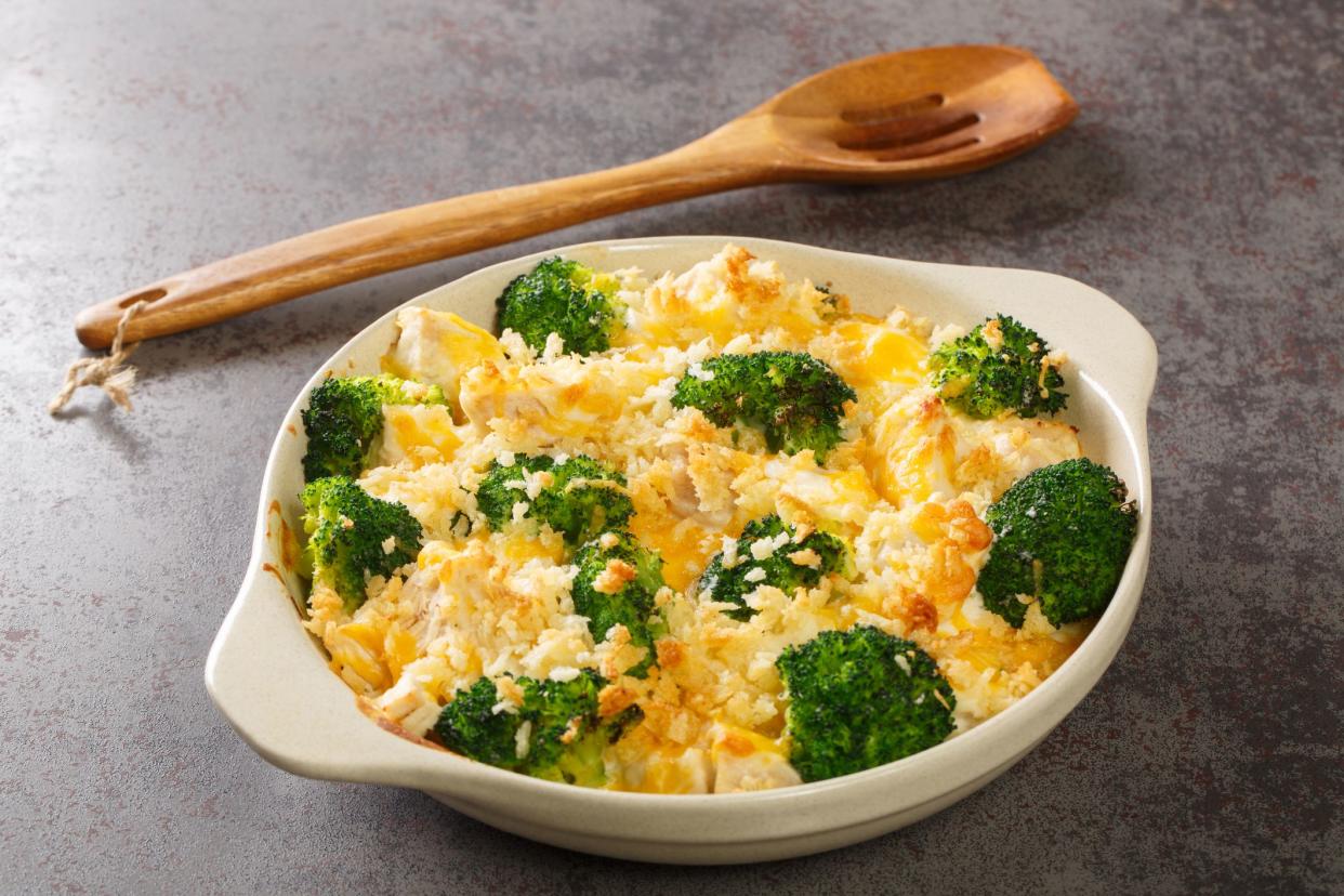 Chicken Divan is full of savory chicken, broccoli, creamy sauce, and the most amazing butter cracker topping close up in the dish on the old table. Horizontal