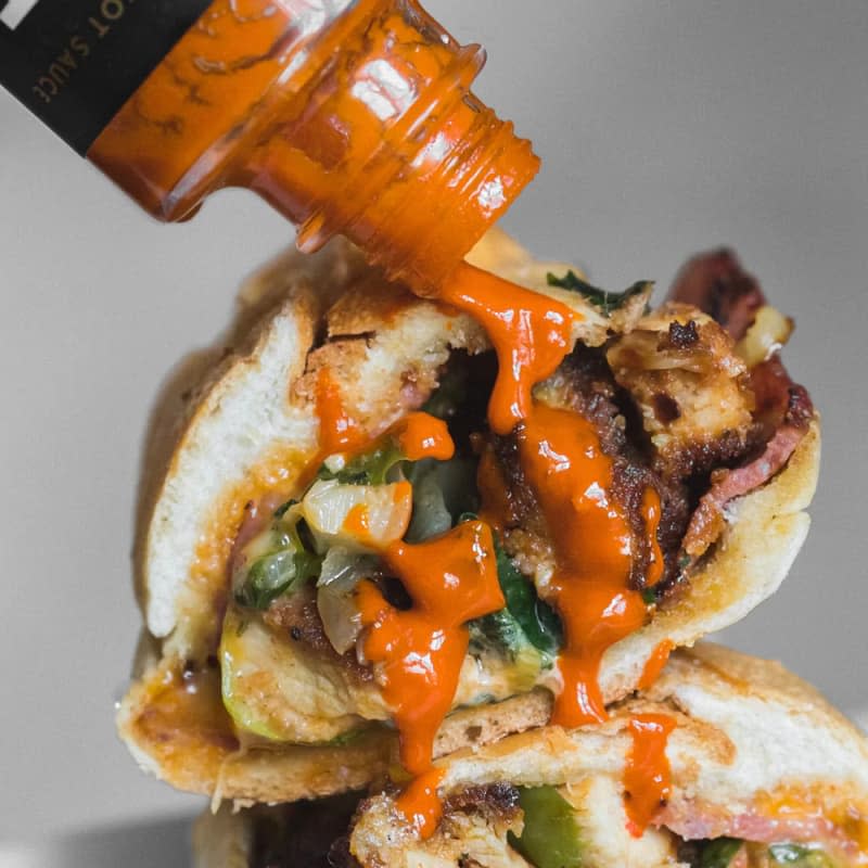 TRUFF original hot sauce being poured onto a sandwich