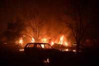 A fire burns a house in Adames area, in northern Athens, Greece, Tuesday, Aug. 3, 2021. Thousands of people fled their homes north of Athens on Tuesday as a wildfire broke out of the forest and reached residential areas. The hurried evacuations took place just as Greece grappled with its worst heat wave in decades. (AP Photo/Michael Varaklas)