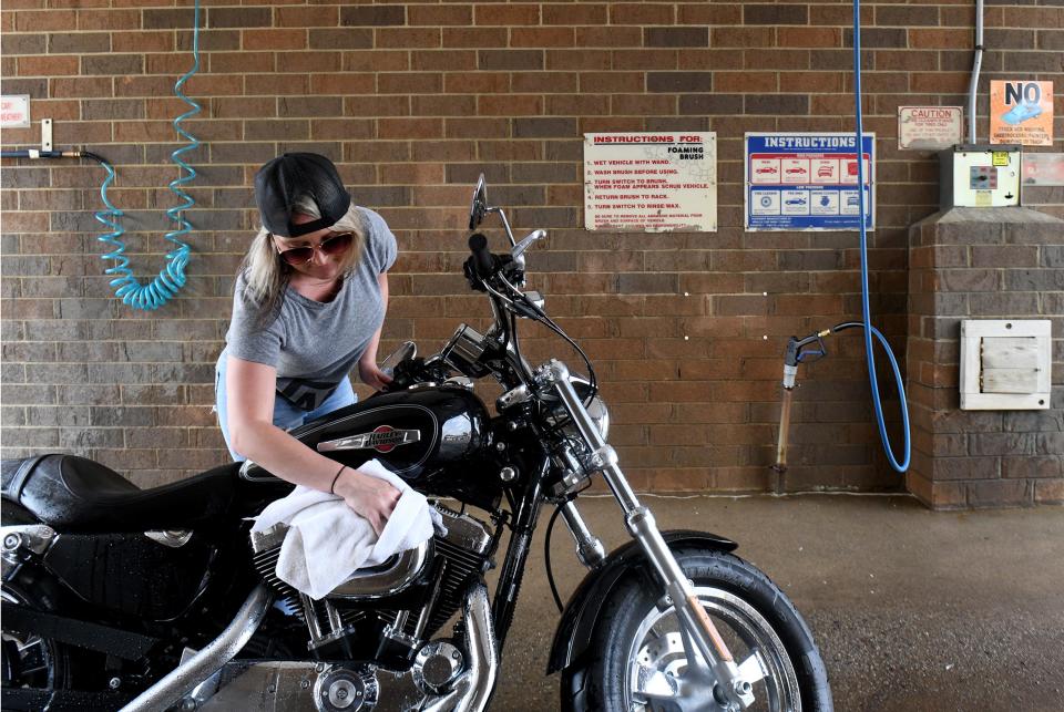 Lindsay Schreckengost of Alliance takes advantage of the warm weather to clean her motorcycle in a self service bay at Roy's Car Wash and Lube in Alliance.