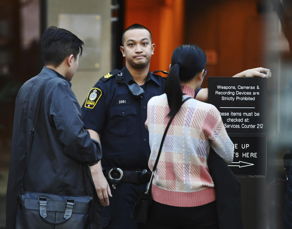 A British Columbia sheriff looks on as people line up at a Vancouver courthouse prior to the bail hearing for Meng Wanzhou, Monday, December 10, 2018. Wanzhou, the chief financial officer of telecommunications giant Huawei and daughter of its founder, was detained at the request of the U.S. during a layover at the Vancouver airport on Dec. 1 (Jonathan Hayward/The Canadian Press via AP)