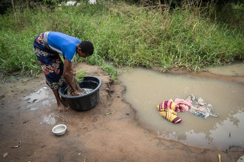 A woman washing clothes in a puddle caused by heavy rains the Metuge region, in the Cabo Delgado province of Mozambique (AFP via Getty Images)