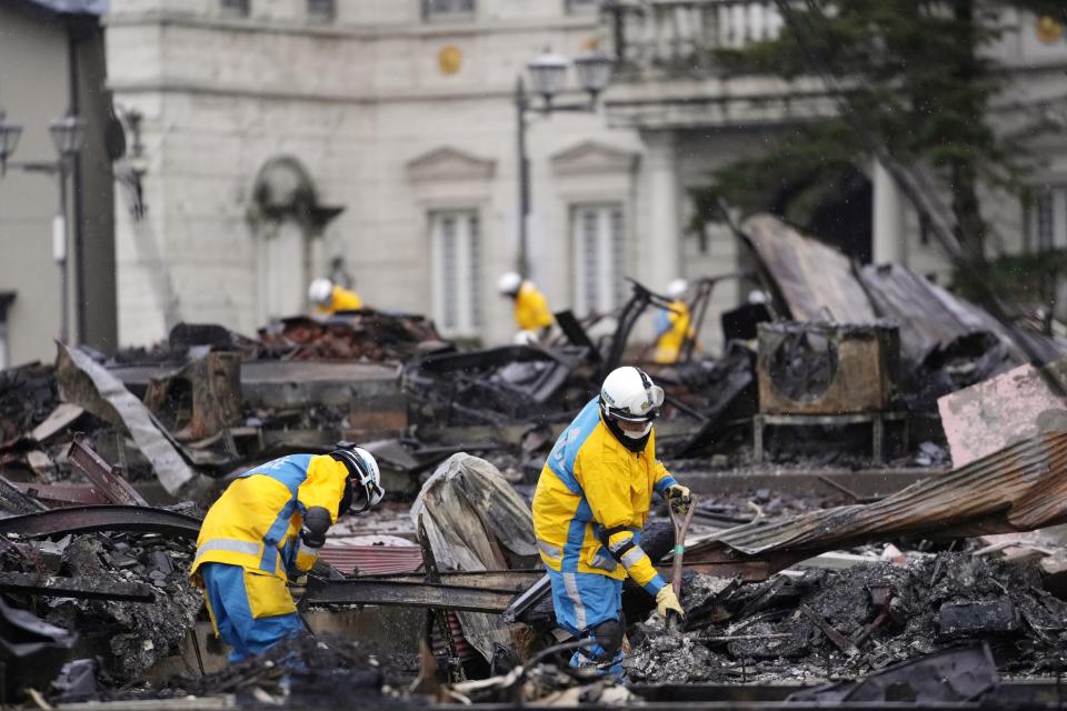 Police officers search victims of a fire caused by powerful earthquake in Wajima in the Noto peninsula facing the Sea of Japan, northwest of Tokyo, Sunday, Jan. 7, 2024. Monday's temblor decimated houses, twisted and scarred roads and scattered boats like toys in the waters, and prompted tsunami warnings. (AP Photo/Hiro Komae)