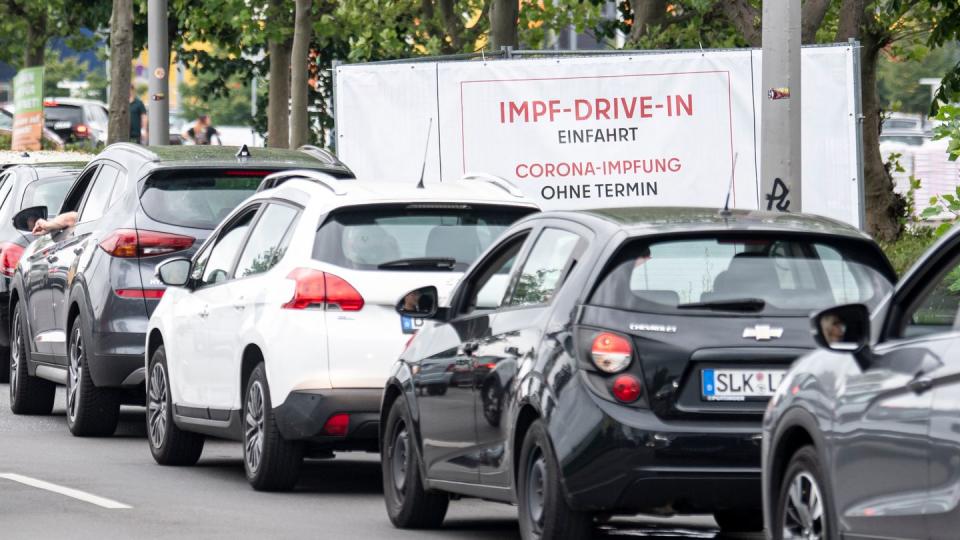 Eine lange Schlange bildet sich vor der Einfahrt zur Impfung an der Ikea-Filiale Lichtenberg vor dem Schild mit der Aufschrift 