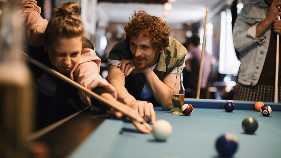 Close up of a group of friend playing pool.