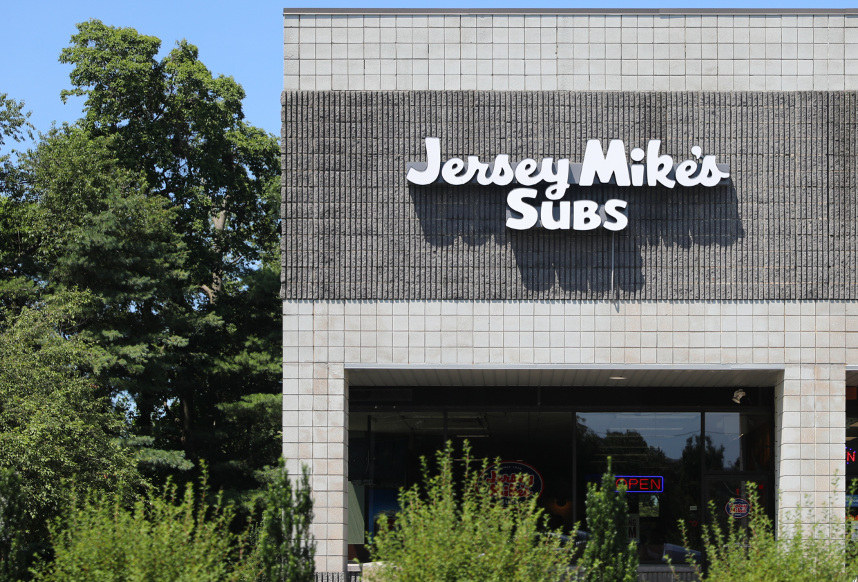 Front exterior of Jersey Mike's Subs, Princeton, New Jersey, surrounded by bushes and trees on a sunny day