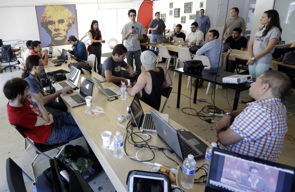 FILE - In this Feb. 1, 2014 file photo, Raul Moas, center rear, executive director of the nonprofit organization Roots of Hope, addresses a group during a "Hackathon for Cuba" event run by Roots of Hope in Miami. A group of technology experts gathered to come up with ways to use their hacking ability to improve Internet access and information in Cuba. Cuba routinely blocks Internet pages that it finds objectionable. Leaders with the largest nonprofit organization for young Cuban-Americans quietly provided strategic support for the federal government’s secret "Cuban Twitter" program, connecting contractors with potential investors and even serving as paid consultants, The Associated Press has learned. For a period of about three months, Moas was significantly involved in the now-defunct ZunZuneo program, including reviewing some of the project’s test text messages to those on the island and approaching potential investors, according to the documents. (AP Photo/Lynne Sladky, File)