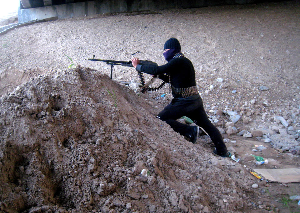 A gunmen takes cover during clashes with Iraqi security forces outside Fallujah, 40 miles (65 kilometers) west of Baghdad, Iraq, Sunday, Jan. 19, 2014. Violence across Iraq, including a series of car bombings and fighting between militants and government troops over control of the country's contested Anbar province, killed dozens Saturday, officials said. (AP Photo)