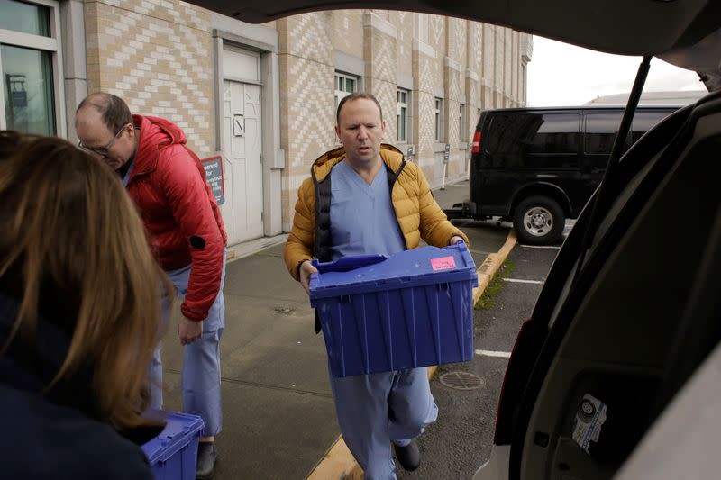 Harborview Medical Center's home assessment team load protective and testing supplies into a van while preparing to visit the home of a person potentially exposed to novel coronavirus at Harborview Medical Center in Seattle