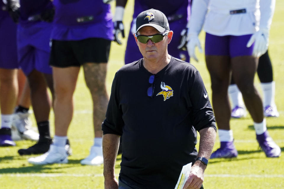 FILE - In this June 16, 2021, file photo, Minnesota Vikings head coach Mike Zimmer walks through the field during NFL football practice in Eagan, Minn. The Vikings and assistant coach Rick Dennison have found a solution for him to remain with the club despite his unvaccinated status. The 63-year-old Dennison will take a role as senior offensive advisor. He'll do all of his collaboration with the staff virtually. (AP Photo/Jim Mone, File)