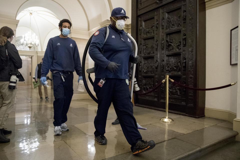 Workers walk through the halls of the U.S. Capitol Building on Capitol Hill, Thursday, April 23, 2020, in Washington. (AP Photo/Andrew Harnik)