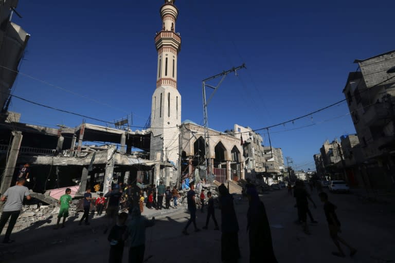 Varias personas caminan junto a un edificio destruido en un bombardeo nocturno israelí en Rafah, en el sur de la Franja de Gaza, el 17 de abril de 2024 (Mohammed Abed)