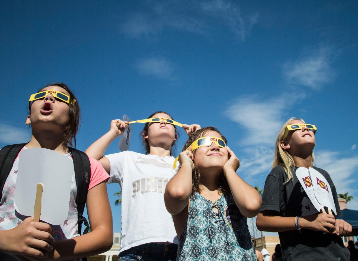 A group of children watch the solar eclipse in 2018 with their protective glasses at the Tempe campus of Arizona State University.