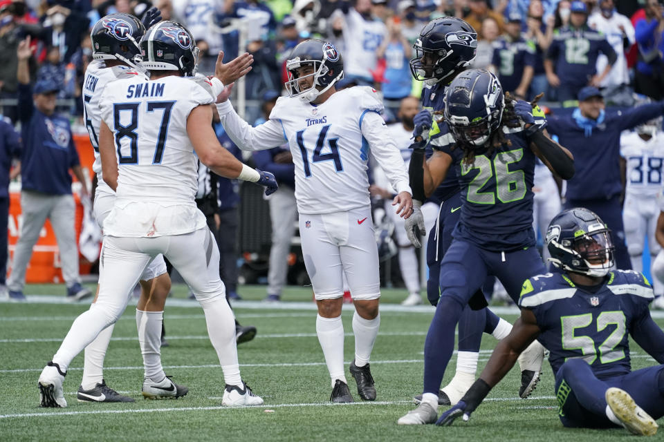 Tennessee Titans kicker Randy Bullock (14) celebrates with tight end Geoff Swaim (87) as Seattle Seahawks defensive back Ryan Neal (26) reacts after Bullock kicked a field goal in overtime to give the Titans a 33-30 win in an NFL football game, Sunday, Sept. 19, 2021, in Seattle. (AP Photo/Elaine Thompson)