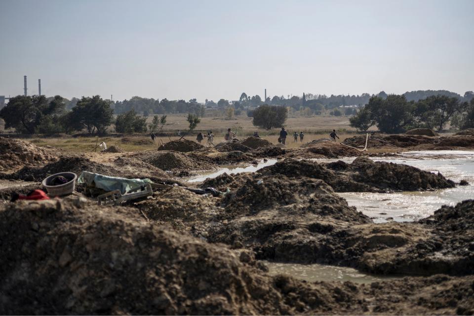 Alleged illegal miners run from security personnel across open ground during a raid to take down an alleged illegal mining operation near Springs, South Africa. 