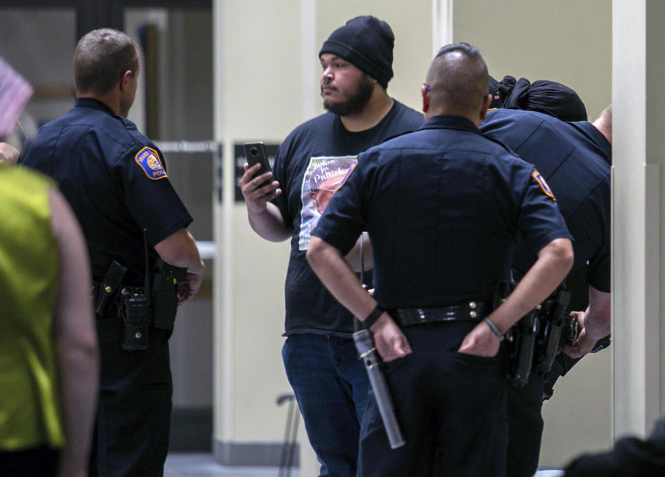 A protester records Grand Rapids police officers on their phone as they place another protester under arrest inside the lobby of the Grand Rapids Police Department after the arraignment of Grand Rapids police officer Christopher Schurr Friday, June 10, 2022 in Grand Rapids, Mich. A judge facing a packed courtroom set bond Friday at $100,000 for Schurr, a Michigan police officer charged with second-degree murder in the death of Patrick Lyoya, a Black man who was shot in the back of the head in April. (Daniel Shular/The Grand Rapids Press via AP)