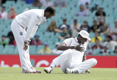 West Indies captain Jason Holder (R) grimaces after failing to catch the ball which hit his right hand during their third cricket test against Australia in Sydney, January 7, 2016. REUTERS/Jason Reed