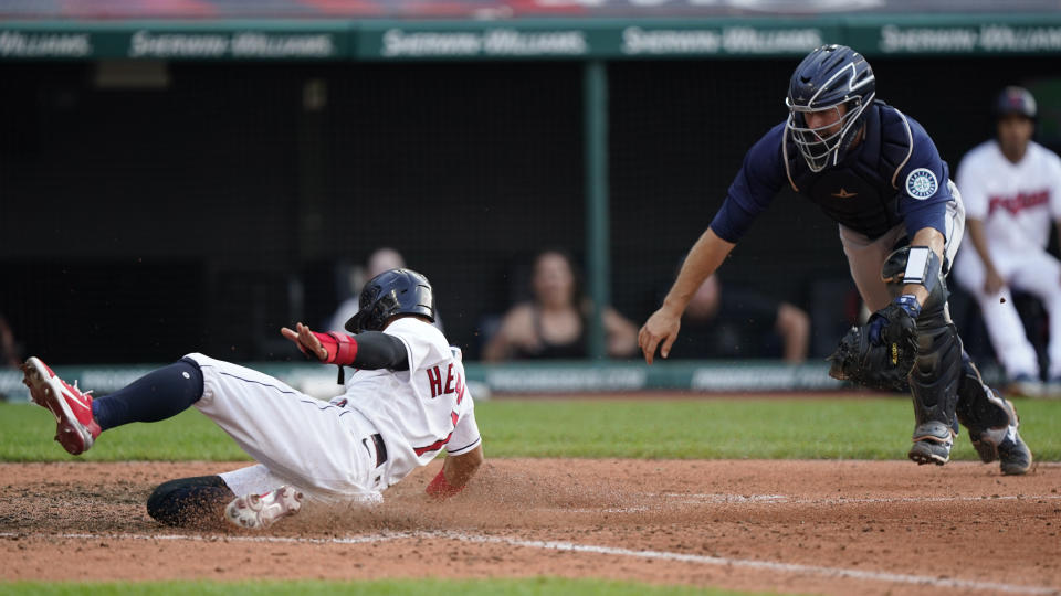 Cleveland Indians' Cesar Hernandez, left, scores as Seattle Mariners catcher Tom Murphy is late on the tag in the 10th inning of a baseball game, Saturday, June 12, 2021, in Cleveland. (AP Photo/Tony Dejak)