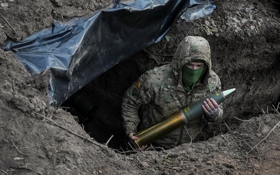 Ukrainian serviceman of the First Presidential Brigade Bureviy (Hurricane) of the National Guard of Ukraine holds an artillery shell as he prepares to fire a howitzer