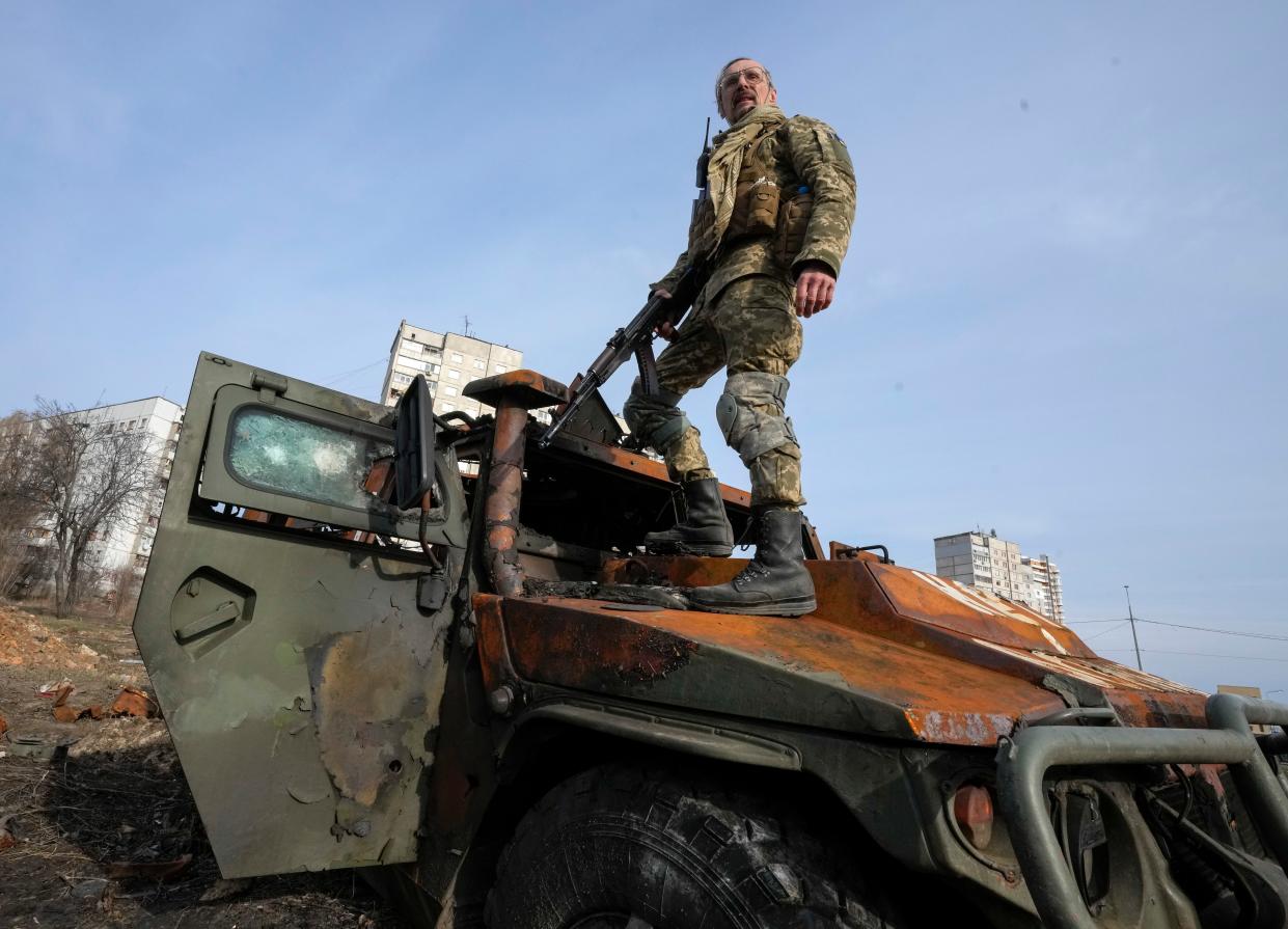 A Ukrainian soldier stands a top a destroyed Russian APC after recent battle in Kharkiv, Ukraine, on Saturday.