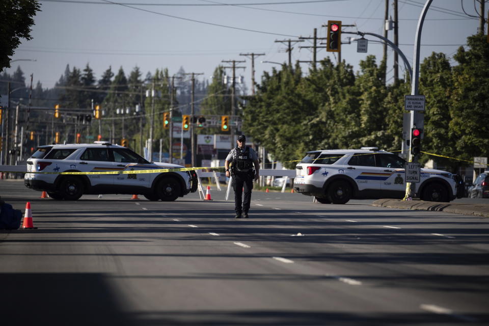 An RCMP officer walks on the road at the scene of a shooting in Langley, British Columbia, Monday, July 25, 2022. Canadian police reported multiple shootings of homeless people Monday in a Vancouver suburb and said a suspect was in custody. (Darryl Dyck/The Canadian Press via AP)