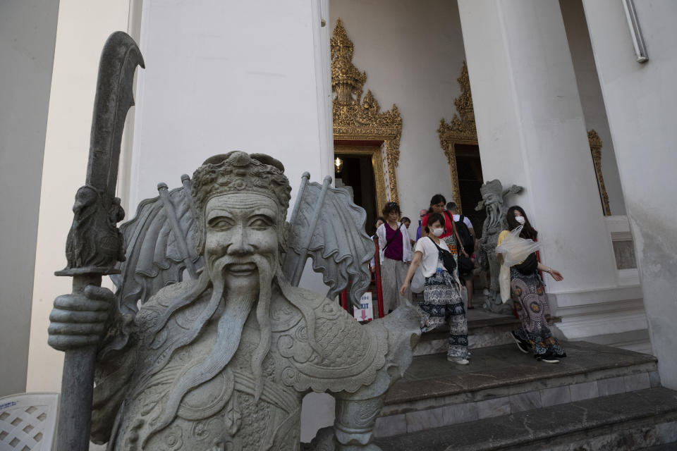 In this Feb. 7, 2020, photo, tourists wearing face masks leave after touring the statue of a giant Buddha at Wat Pho in Bangkok, Thailand. There were less crowds in Bangkok&#39;s popular Wat Pho, a centuries-old Buddhist temple known for its giant reclining buddha, due to the virus scare. The complex of temples is normally visited by thousands of tourists. (AP Photo/Sakchai Lalit)