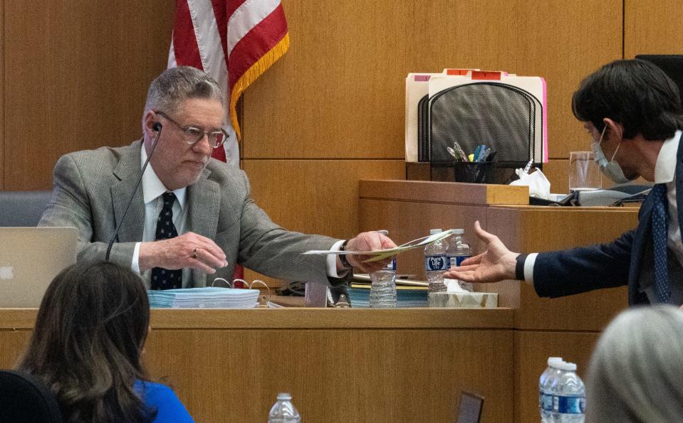 Defense attorney Richard Parker (right) hands Mark Cunningham papers while he testifies during the Bryan Miller trial on Jan. 16, 2023, in Maricopa County Superior Court in Phoenix, Ariz.