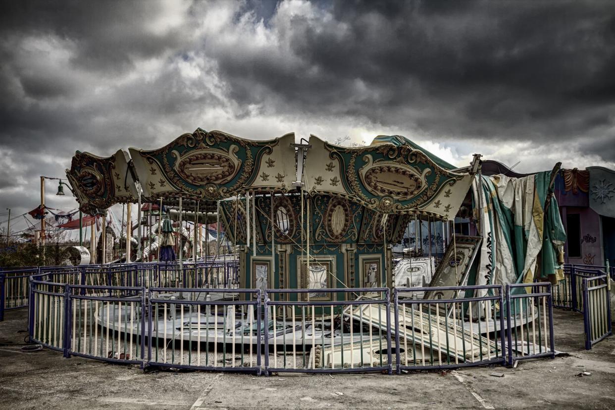 Abandoned circle ride, Six Flags New Orleans, dramatic dark grey stormy sky, other abandoned rides in the background