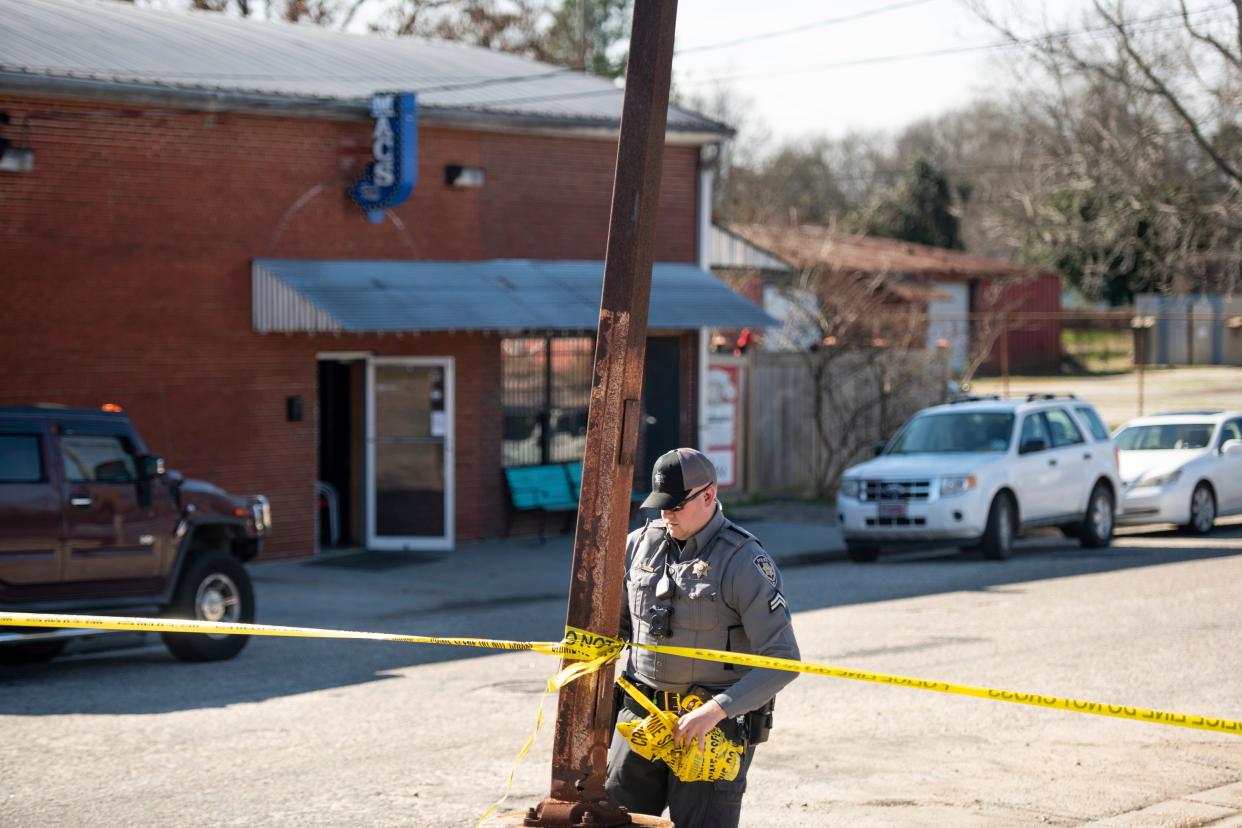 A law enforcement officer removes crime scene tape in front of Mac's Lounge, the scene of an early morning bar shooting on Jan. 26, 2020, in Hartsville, S.C.