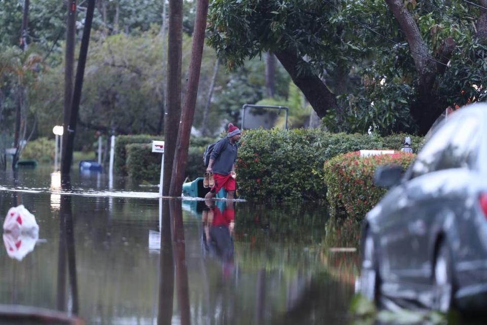 A man walks through flood waters while carrying his shoes in North Miami in the morning of Thursday, Nov. 16, 2023. Courtesy of Cory Boehne