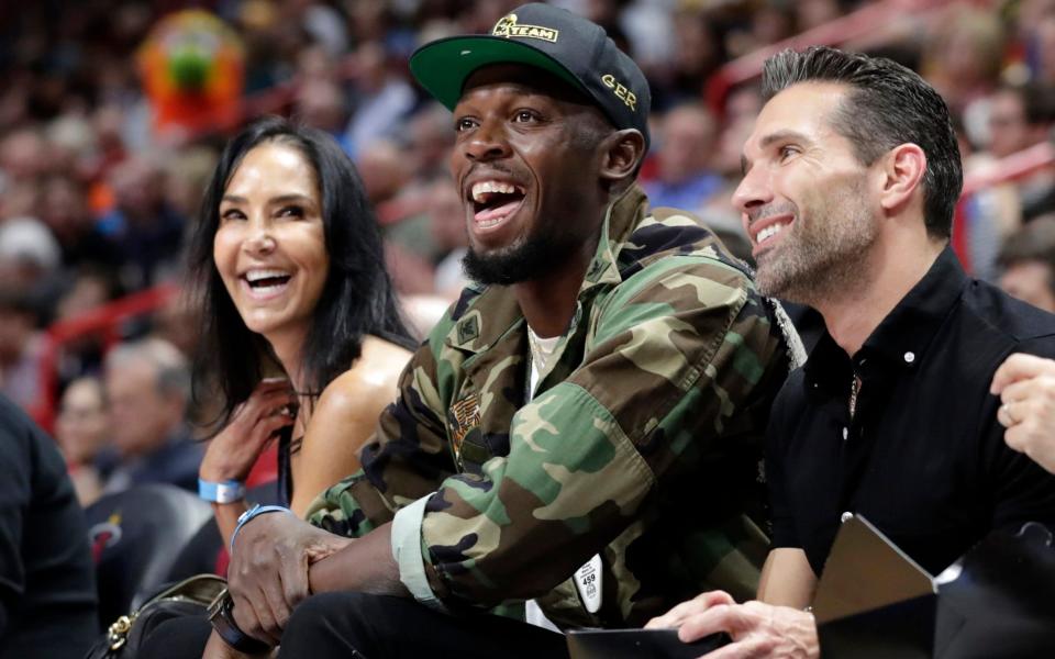  Usain Bolt watches the first half of an NBA basketball game between - AP