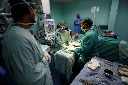 Palestinian surgeon Hafez Abu Khousa (R) looks at a screen as he is guided by doctor Ghassan Abu Sitta in Beirut during a Proximie surgery, in the operating room at Al Awda Hospital in the northern Gaza Strip April 30, 2016. REUTERS/Suhaib Salem