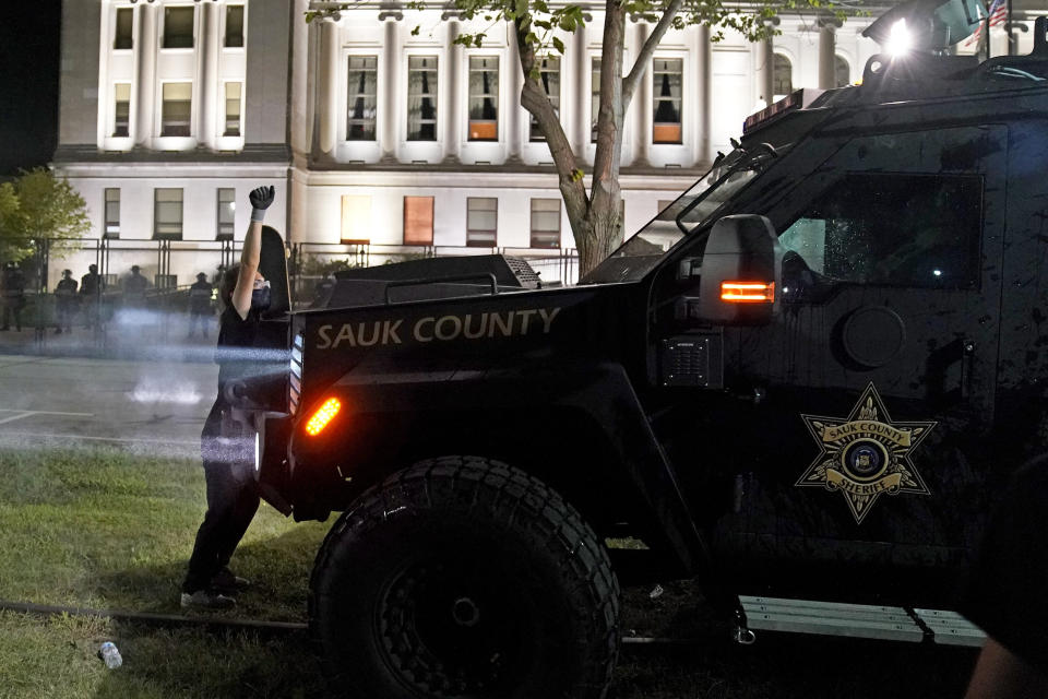 A protester obstructs an armored vehicle attempting to clear the park of demonstrators during clashes outside the Kenosha County Courthouse late Tuesday, Aug. 25, 2020, in Kenosha, Wis. Protests have erupted following the police shooting of Jacob Blake two days earlier. (AP Photo/David Goldman)