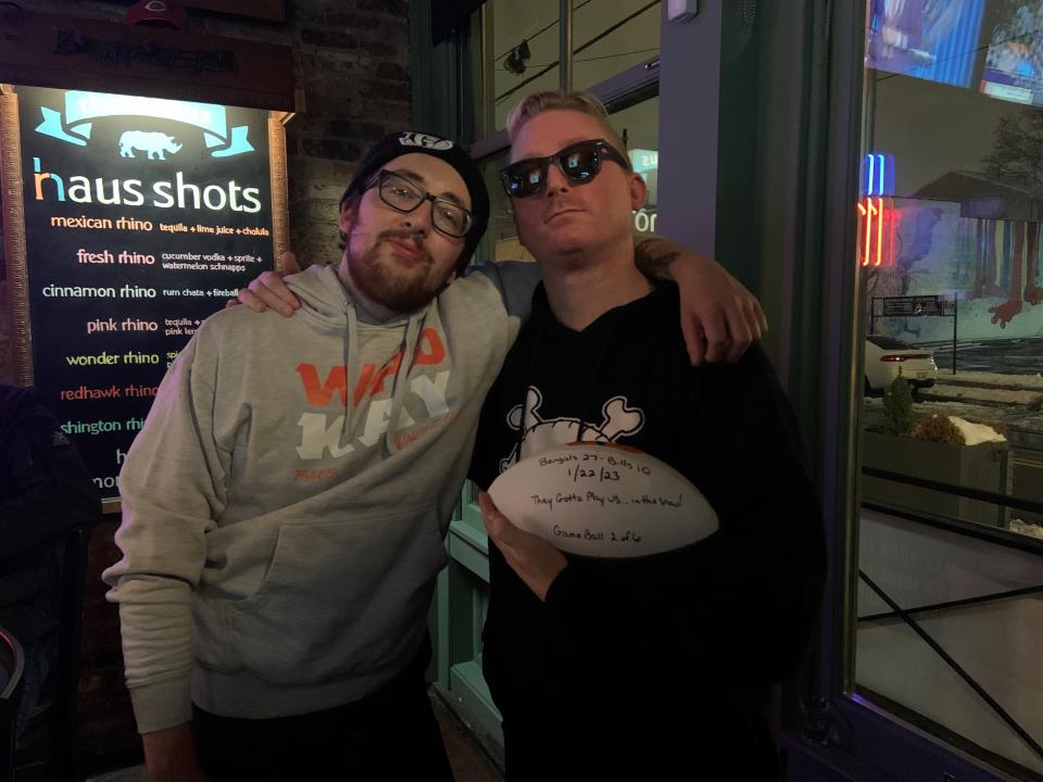 Rhinehaus bartenders Danny Samet (left) and Wendell Brown (right) hold the game ball that was delivered to the bar after the Bengals' win against the Buffalo Bills on Sunday.