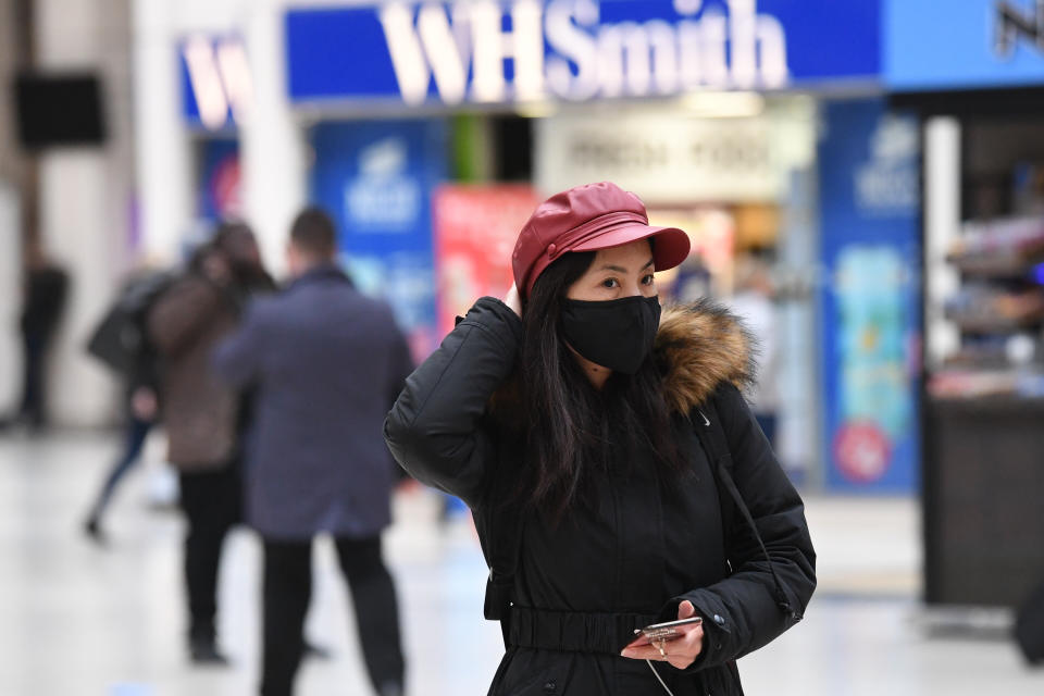 A woman wearing a face mask on her phone at Victoria Station in London.