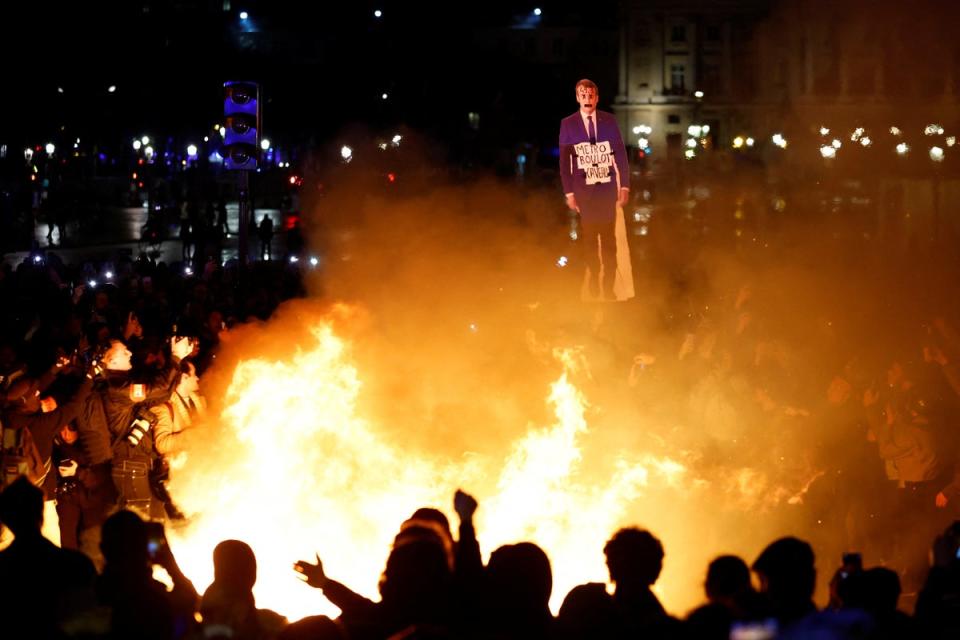 Protesters holds a cut-out of French President Emmanuel Macron near a fire in Paris  (REUTERS)