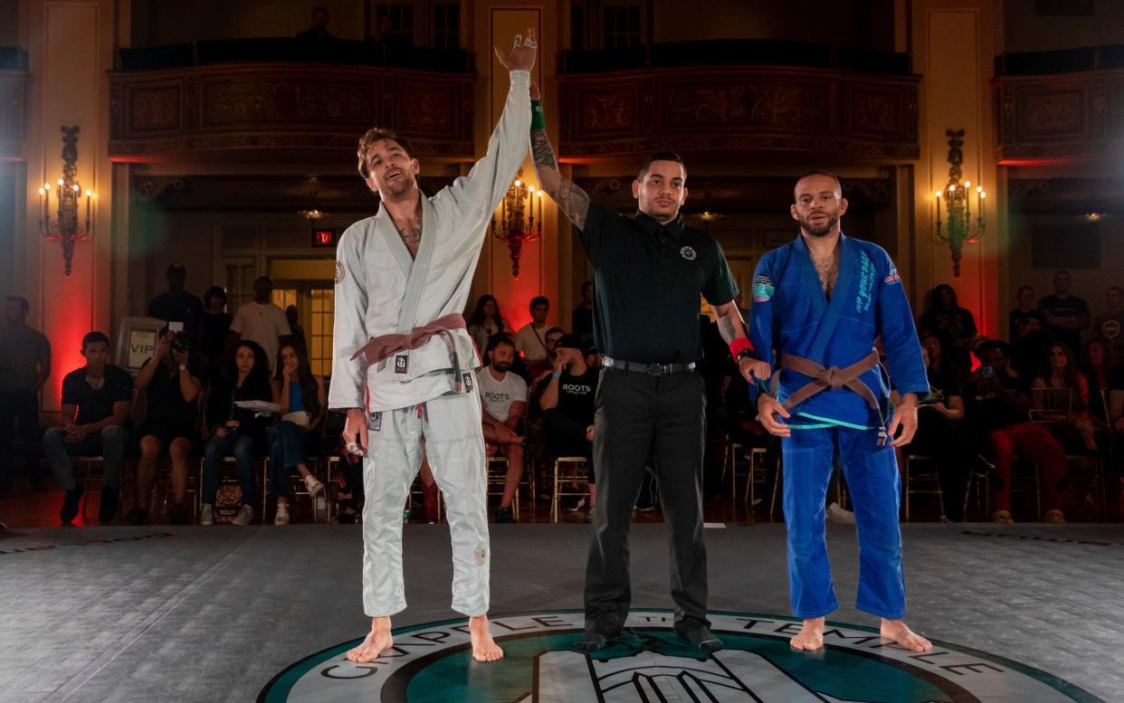 Zach Mabey, left, a brown belt in Brazilian jujitsu, gets his hand raised by Cauata Rocha, a referee, after winning his match against Lear Kirkland during their match at the Grapple in the Temple jujitsu tournament inside the Masonic Temple in Detroit on Friday, Aug. 11, 2023.